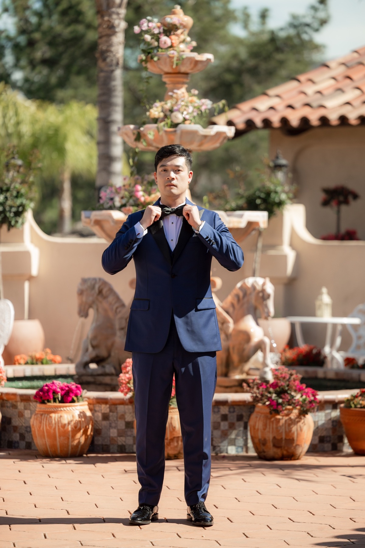 Michael Tran adjusting his bow tie in a custom Kavalier wedding tuxedo